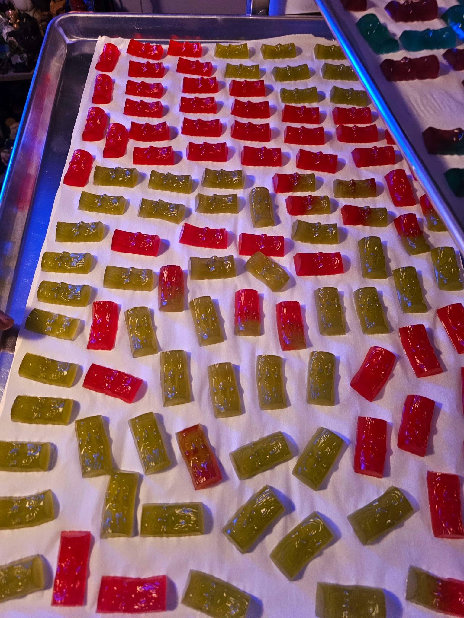 Red and green gummies on a tray drying on parchment paper